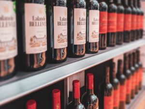 Close-up of a mix of red and wine bottles on a metal shelf, for sale in a store.